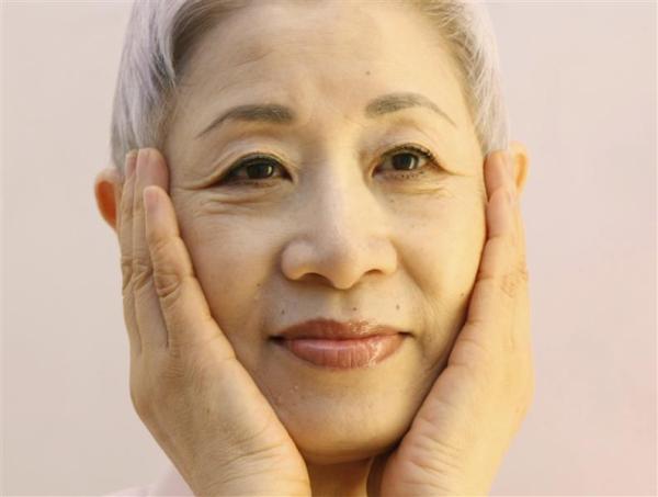 Japanese beauty expert Chizu Saeki cups her cheeks, which is part of her facial care, at her salon in Tokyo